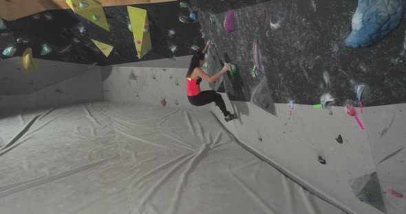 Moving Up Female Climber Training on a Climbing Wall Young Woman Practicing Rockclimbing Mountaineer alt