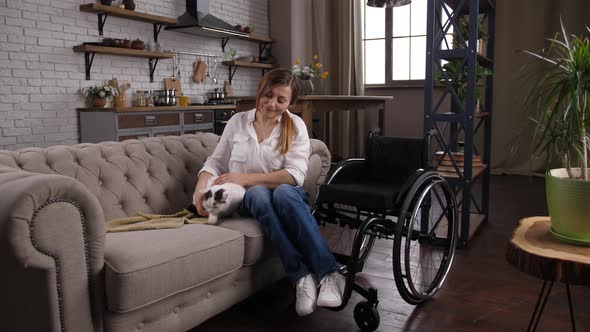 Positive Handicapped Female Caressing Cat on Couch alt