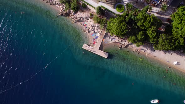 Vertical Aerial Drone View of the Tourists Jumping to the Sea From the Pier