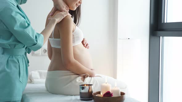 Pregnant Woman Receiving Back Massage From Masseur in Spa Cabinet Sit with Candles alt