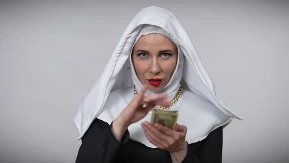 Gorgeous Woman in Nun Costume Scattering Money in Slow Motion Crossing Hands Looking at Camera alt
