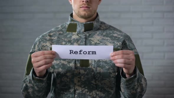 Reform Word Written on Sign in Hands of Male Soldier, Military Law Amendment alt