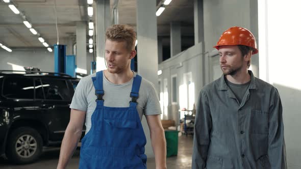 Factory Worker in a Hard Hat is Walking Through Industrial Facilities Service Workshop Factory Car alt
