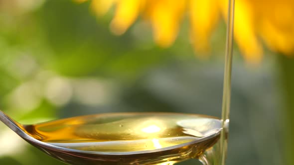 Slow Motion of Pouring Sunflower Oil Liquid Into Spoon on Nature Background alt