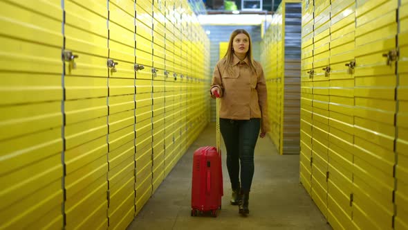 Dolly Shot of Beautiful Caucasian Woman Walking with Red Rolling Suitcase in Warehouse with Yellow alt