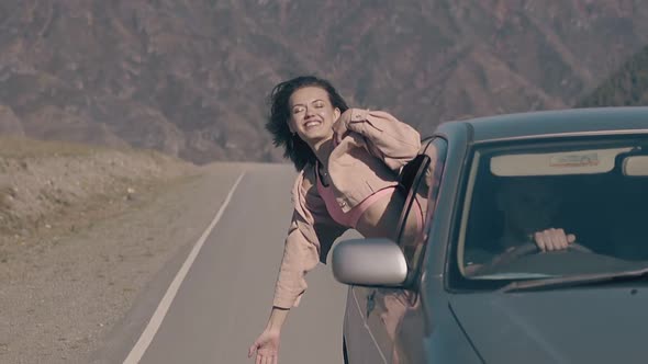 Brunette Looks Out of Driving Car and Smiles Enjoying Life alt