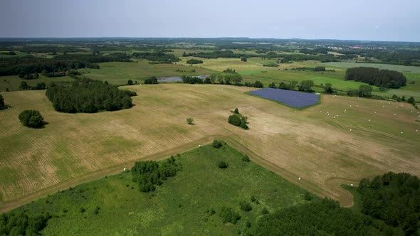 Aerial view of a large agricultural field after harvesting on a sunny day with a small solar panel f alt