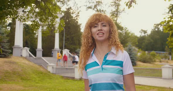 Happy Cool Blondehaired Woman Wearing Headphones Dancing Alone in a Park at Sunset alt