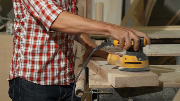 Male Carpenter Polishing Piece of Wood at His Workshop alt