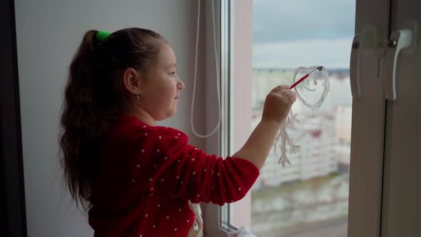 Child draw santa's gnome on window with white paints close-up. Caucasian female person decorate room