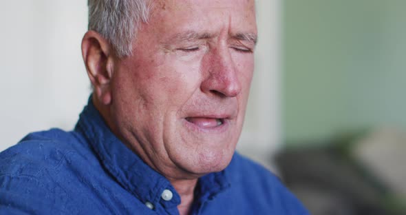 Portrait of senior caucasian man coughing or sneezing into his arm alt