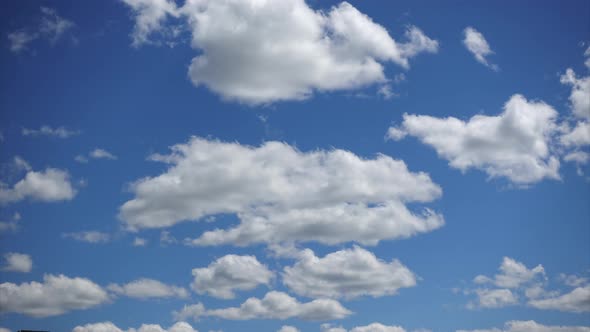 Beautiful white clouds moving fast high in the blue sky, Time-lapse. Sunny sky on a summer day`