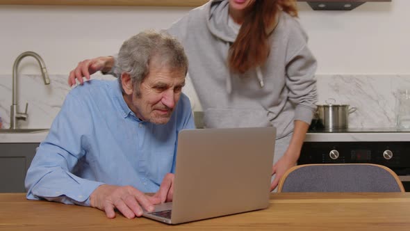 Happy Grandfather and Daughter Hugging Looking at Something on a Laptop at Home alt