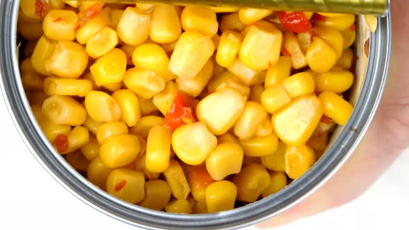 Hand Opens Metallic Tin Can of Marinated Sweet Corn with Vegetables alt