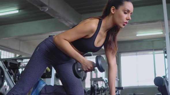 Sporty woman lifting dumbbell in fitness