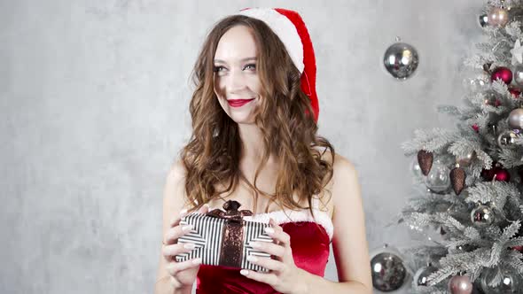 Woman in Red Dress Looks for Present Near Christmas Tree alt