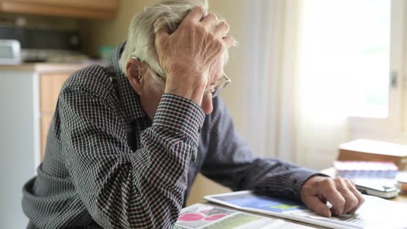 Senior Man Thinking While Reading Newspaper By The Window alt