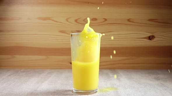 Ice Cube Drops in a Glass With Orange Juice