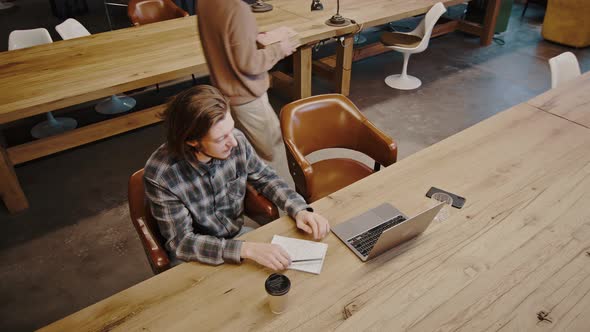 Man and Woman Groupmates Making Project Together at Library Lady Bringing Stack of Books for alt