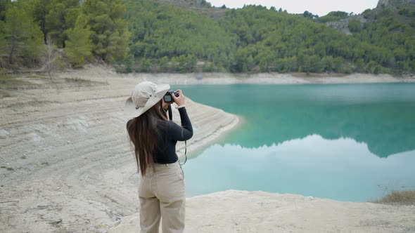 Young Woman Walks and Takes Pictures of Still Lake and Forest in Spain alt