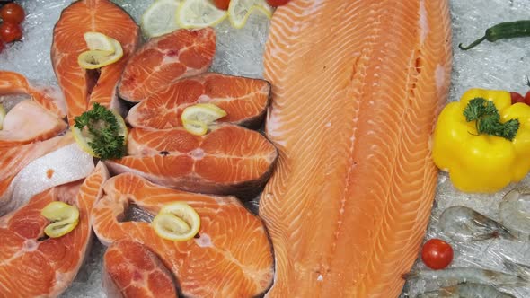 Composition of Trout and Salmon Steaks Lies on Ice in Showcase of Supermarket alt
