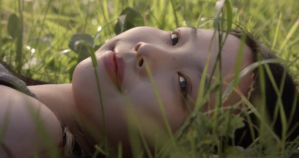 Young Asian Woman Lying on the Meadow with Wind Blowing in Winter Day