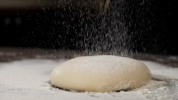 The White Flour is Falling on the Dough in Slow Motion