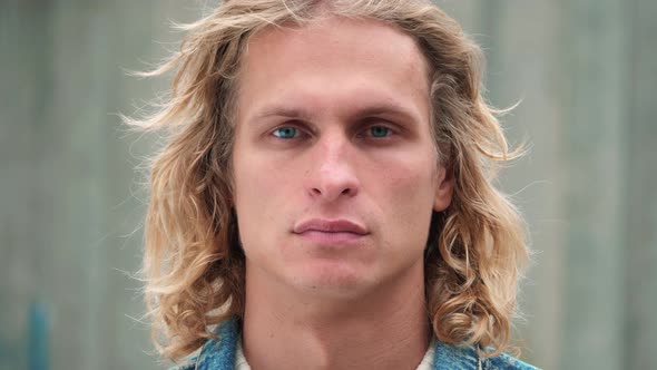 portrait of handsome blue-eyed guy with blond long curly hair