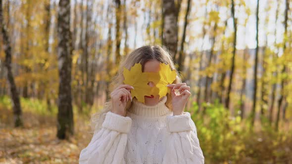 Portrait of a Smiling Happy Cheerful Woman with Two Yellow Leaves Covering Her Face alt