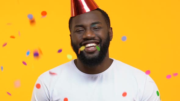 Happy Afro-American Man in Party Hat Under Falling Confetti, Birthday Surprise alt
