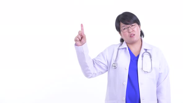Stressed Overweight Asian Woman Doctor Talking While Pointing Up alt