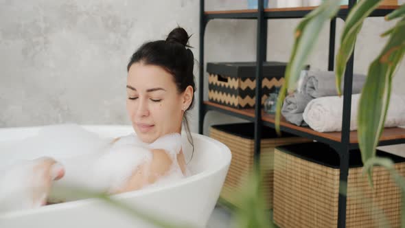 Beautiful Lady Washing in Bathtub Cleaning Skin with Foam Smiling Enjoying Relaxation at Home alt
