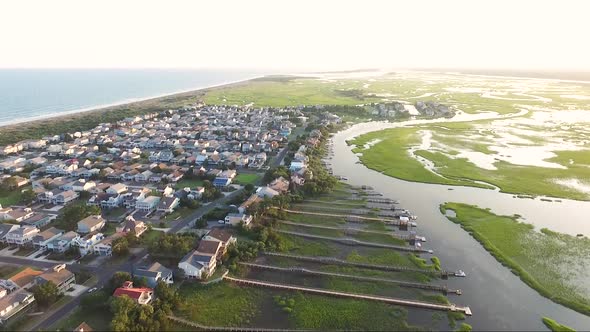 Drone shot of Ocean Isle Beach at sunset near the causeway overlooking piers and houses on the water alt