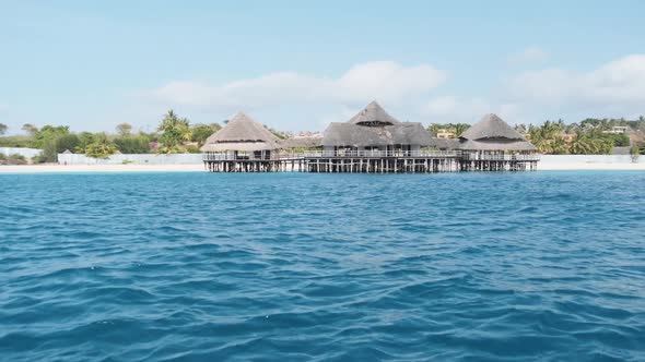 African Restaurant with Thatched Roof on Wooden Poles Above the Ocean alt