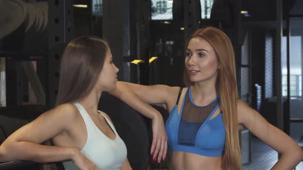 Two Beautiful Fitness Women Smiling To the Camera at the Sports Studio alt