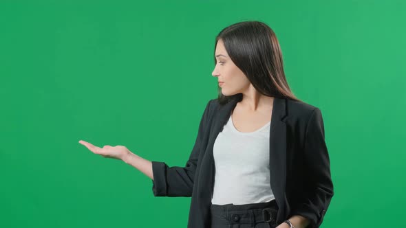 Young Business Woman Presenting Product on Green Background. Portrait of Female Professional alt