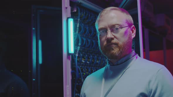 Portrait of Data Center Engineer in Server Room with Neon Light alt