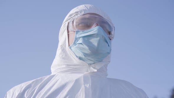 Close-up Portrait of Young Caucasian Man in White Safety Suit and Protective Eyeglasses at the alt