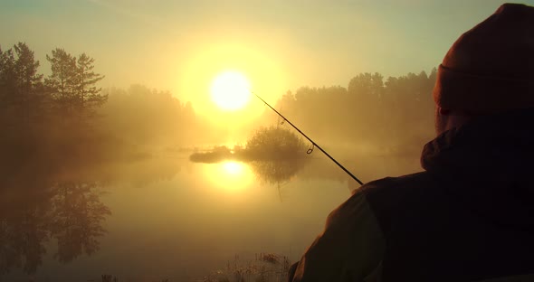 Unrecognizable Man Fishing in Lake at Dawn