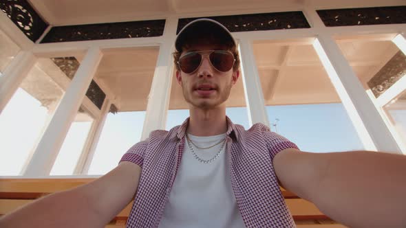 POV Man Sat On Bench At Seaside Watching Sport On His Smart Phone In Slow Motion alt
