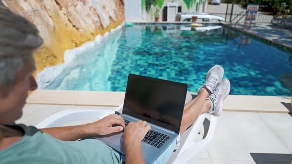 Side View Man Lying By the Pool and Working on Laptop Computer with White Blank Screen Male Hands alt