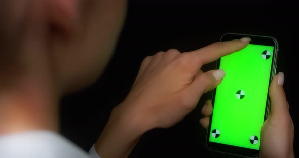 Woman Using Mobile App on Green Screen Phone Swipes Down