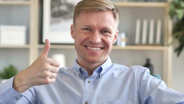 Thumbs Up By Businessman at Work Looking at Camera alt