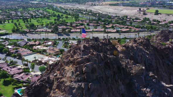 Aerial Shot of American Flag on top of Mountain with City in the Background alt