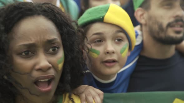 Brazilian soccer fans watching match at stadium with look of disappointment alt