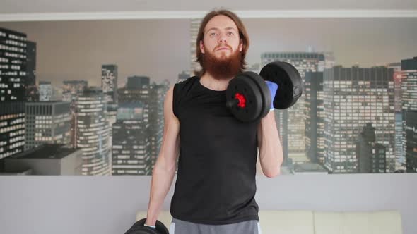 Man using dumbbells doing workout at home. Bearded man training biceps.