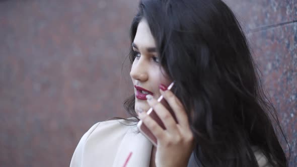 Stylish Girl Dials a Phone Number and Talks on the Street at the Background alt