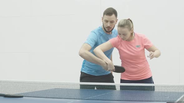 Concentrated Female Coach Showing Right Movement of Hand in Ping-pong To Young Caucasian Man alt