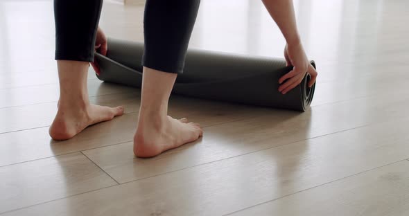 Closeup Attractive Woman Unfolds a Rug for Practicing Yoga at Home alt