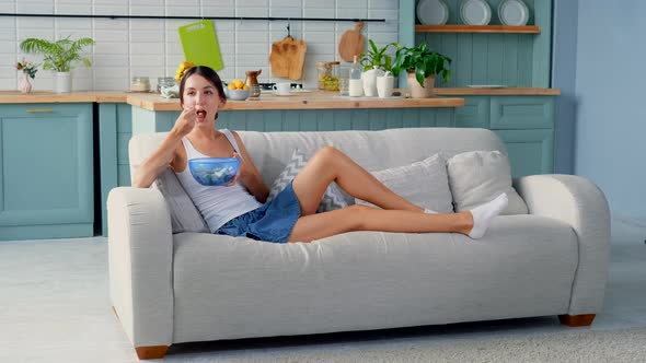 Cute Girl Eating Fruit Salad Sitting On Sofa